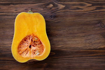 Half of raw organic butternut squash, wood background. Top view with copy space.