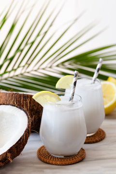 Coconut Cocktail In Glasses With Lemon And Drinking Straw. White Background. Copy Space