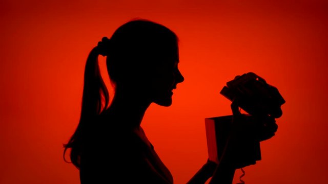 Silhouette of surprised young woman opening gift box on Christmas eve. Female's face in profile with birthday present. Black contour shadow of happy teenager's half-face celebrating