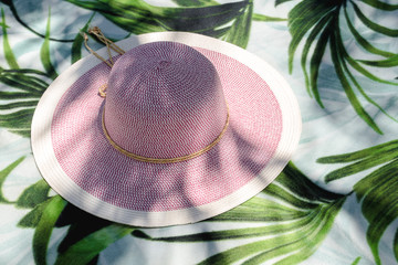 Straw hat lying on a beach underlay with palm illustartion.