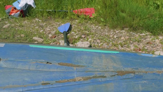 Process of reparing canoe. Man tapes hole on bottom of canoe