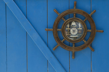  The steering wheel of the ship on blue  wooden wall.
