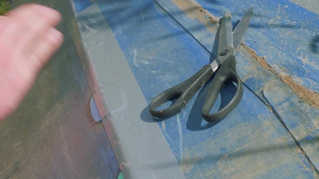 Process of reparing canoe. Man tapes hole on bottom of canoe