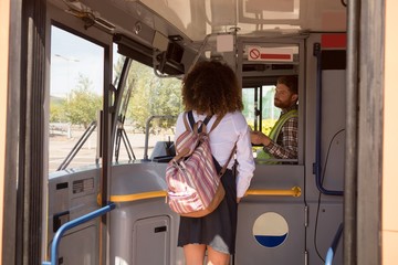 Female commuter taking ticket from driver in modern bus