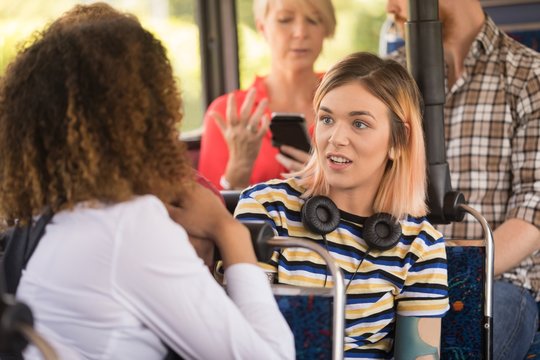 Female friends interacting while travelling in modern bus