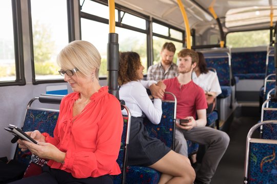 Female commuter using mobile phone while travelling in bus
