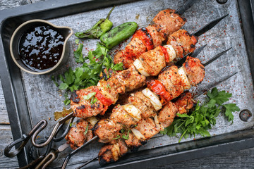 Traditional Greek souvlaki barbecue skewer with tomato, onion and paprika as closeup on a metal...