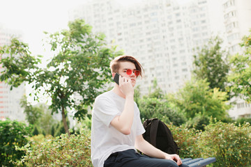 Student with phone in hands sits in park. Outdoor