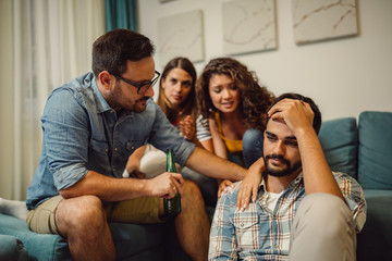 Group of young people comforting their upset friend while discussing problems at home