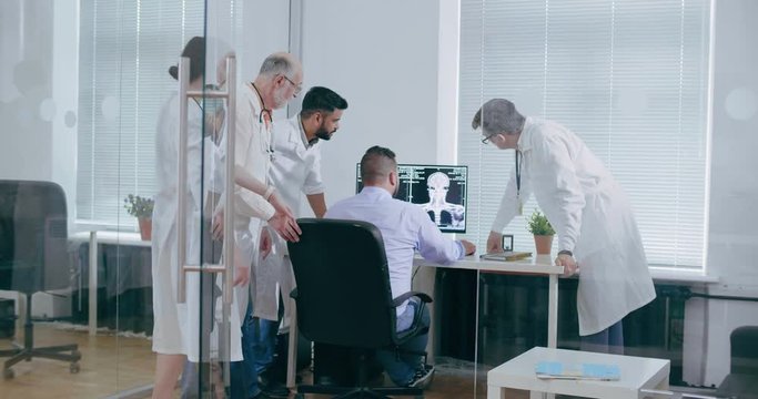 Group of doctors look at picture of brain standing at the computer