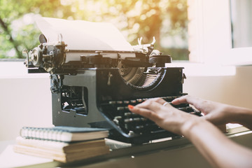 Woman's  hands writing on a vintage typewriter. Young woman writer at home, work on typewriter.