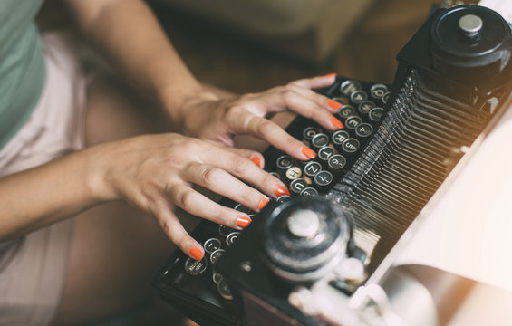 Woman's  hands writing on a vintage typewriter. Young woman writer at home, work on typewriter.