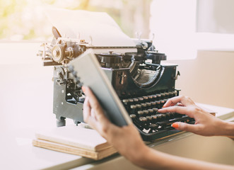 Fototapeta premium Woman's hands writing on a vintage typewriter. Young woman writer at home, work on typewriter.