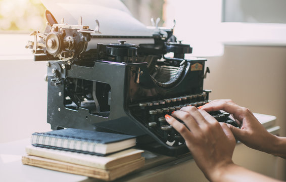 Woman's  hands writing on a vintage typewriter. Young woman writer at home, work on typewriter.