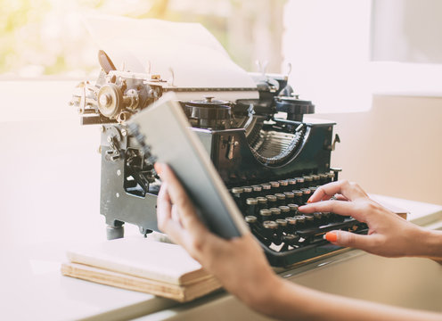 Woman's  hands writing on a vintage typewriter. Young woman writer at home, work on typewriter.