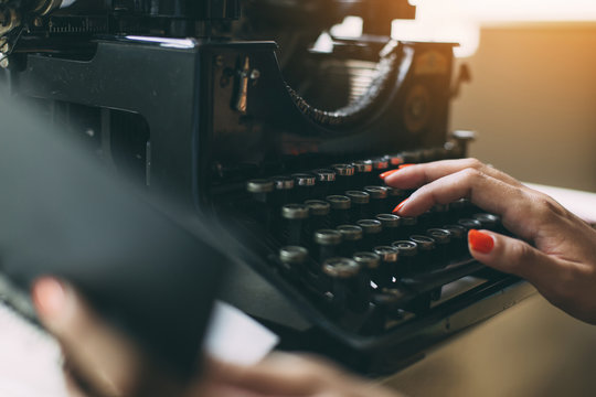 Woman's  hands writing on a vintage typewriter. Young woman writer at home, work on typewriter.
