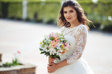 Naklejka premium A beautiful bride in a white wedding dress and with a bouquet of flowers enjoying the moment. Wonderful mood, beautiful waves, great atmosphere. wedding concept.