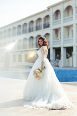 Obraz premium A beautiful bride in a white wedding dress and with a bouquet of flowers enjoying the moment. Wonderful mood, beautiful waves, great atmosphere. wedding concept.