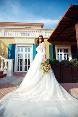 Obraz premium A beautiful bride in a white wedding dress and with a bouquet of flowers enjoying the moment. Wonderful mood, beautiful waves, great atmosphere. wedding concept.