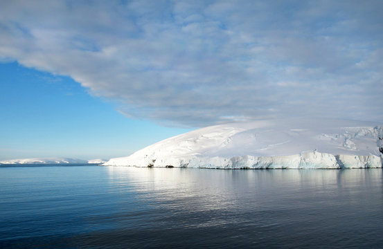 Antarctic ocean, Antarctica. Glacier Snow Covered Mountain. Dramatic blue Sky background
