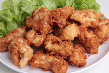 Crispy deep fried chicken served with green oak .