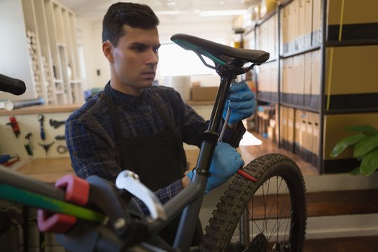 Man adjusting bicycle seat with spanner