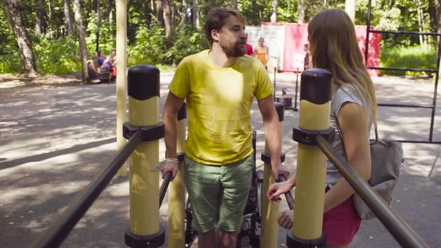 Disable man holding the parallel bars standing on his legs and smiling