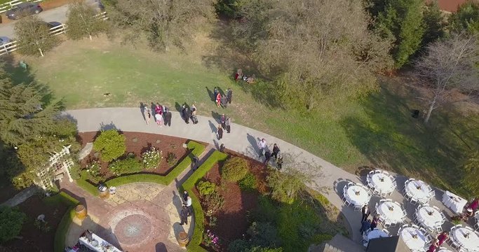 Slowly rotating aerial shot of people moving and gathering together at the historic Annie Nugent home located in Wine Country Watsonville, California.