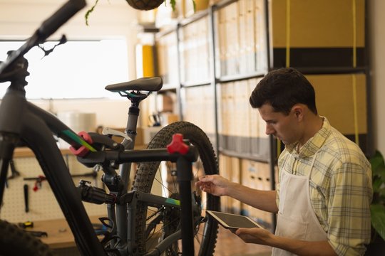 Man using digital tablet while repairing bicycle