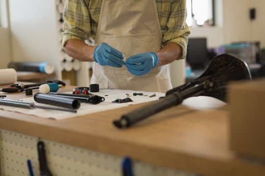Man cleaning bicycle parts on counter in workshop