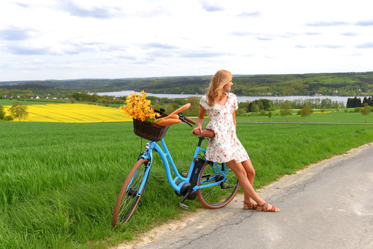 A young woman relaxes from riding her e-bike. She takes time out to enjoy the scenic view of the rolling landscape that lies around her.