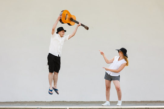 Man jumping with guitar, woman pointing at him