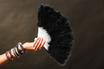 woman holding black feather fan in hand