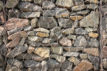 background. the stone fence is covered with iron wire