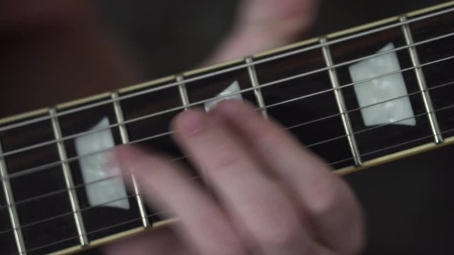 Close up shot of fingers playing a riff on a Les Paul style guitar