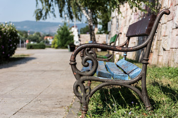 Wooden bench for relaxation in summer weather in park on sunny day. Stylish bench is empty and nobody. Close up, selective focus