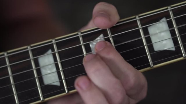 Close up shot of a man's fingers playing guitar riffs