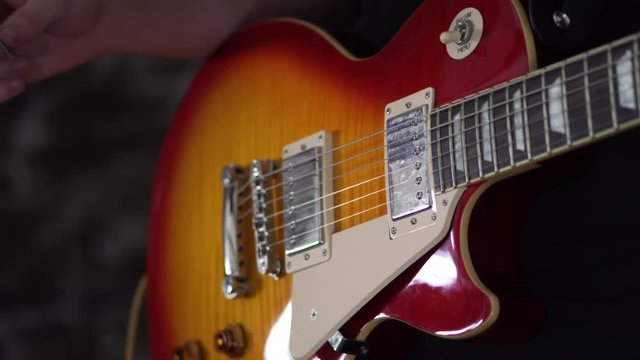 Man playing strumming the last chord of the song on a Les Paul style guitar