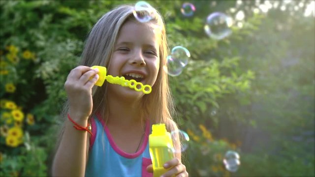 Happy child blowing soap bubbles in park. Slow motion. Stock footage.