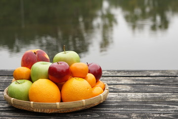 A basket of colorful various kinds of fruit on the wooden dock with the pond on the background, Autumn in Ga USA.