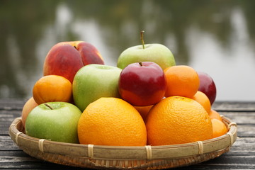 A basket of colorful various kinds of fruit on the wooden dock with the pond on the background, Autumn in Ga USA.