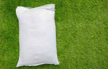 Fertilizer and soil white bag on green grass background