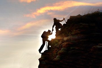silhouette Young couple  hikers climbing up on the peak of mountain. Climbing ,Helps and Team work...