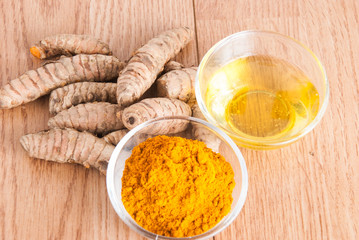 Turmeric powder and fresh turmeric on wooden background.