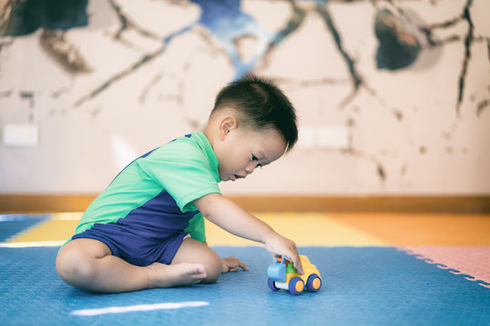 Asian Kid Boy Toddler Playing With Toy Car Indoors Home.