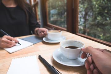 Closeup image of two businessman drinking coffee while talking and meeting in office