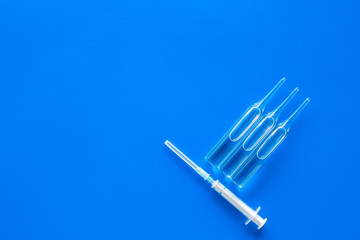 Flu vaccination concept. Syringe and ampoulie on blue background top view copy space
