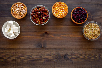 Vegan protein source. Legumes, nuts, cheese. Raw beans, chickpeas, lentil, almond, hazelnut on dark wooden background top view space for text