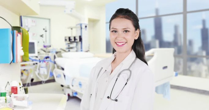 Young female physician standing in the hospital room and smiling at the camera. Shot in 4k resolution