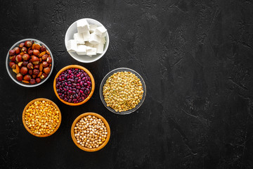 Products rich protein. Legumes, nuts, low-fat cheese. Raw beans, chickpeas, lentil, almond, hazelnut on black background top view space for text